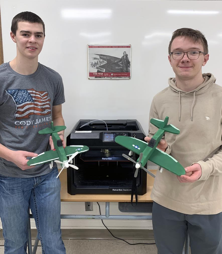 Engineering technology students Coulter Thone (left) and Tucker Banck hold their completed P-47 Thunderbolt model planes. Wood was used to construct the model’s body, main wing and tail wing with accessories designed and made from plastic using the Makerbot 3-D printer pictured in the background. Submitted Photo