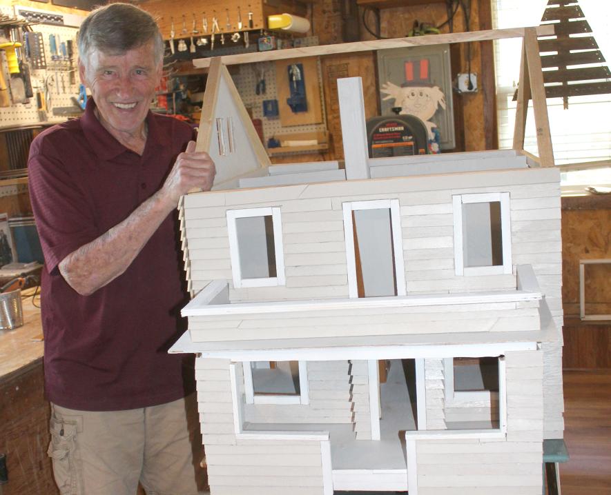 Keith Erickson stands next to the dollhouse he built as a replica of his own house.