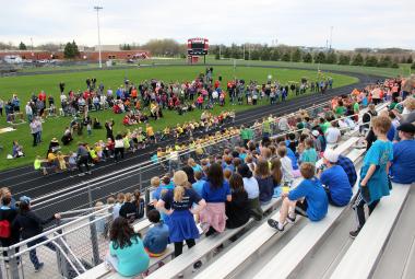 Luverne Elementary students sit in the bleachers as parents stand on the inside of the track to watch the first-grade compete in the tug-of-war competition May 1 as part of the Cardinal Dash activities. Mavis Fodness/Rock County Star Herald Photo