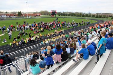 Luverne Elementary students sit in the bleachers as parents stand on the inside of the track to watch the first-grade compete in the tug-of-war competition May 1 as part of the Cardinal Dash activities. Mavis Fodness/Rock County Star Herald Photo