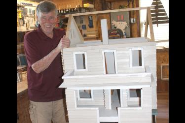 Keith Erickson stands next to the dollhouse he built as a replica of his own house.
