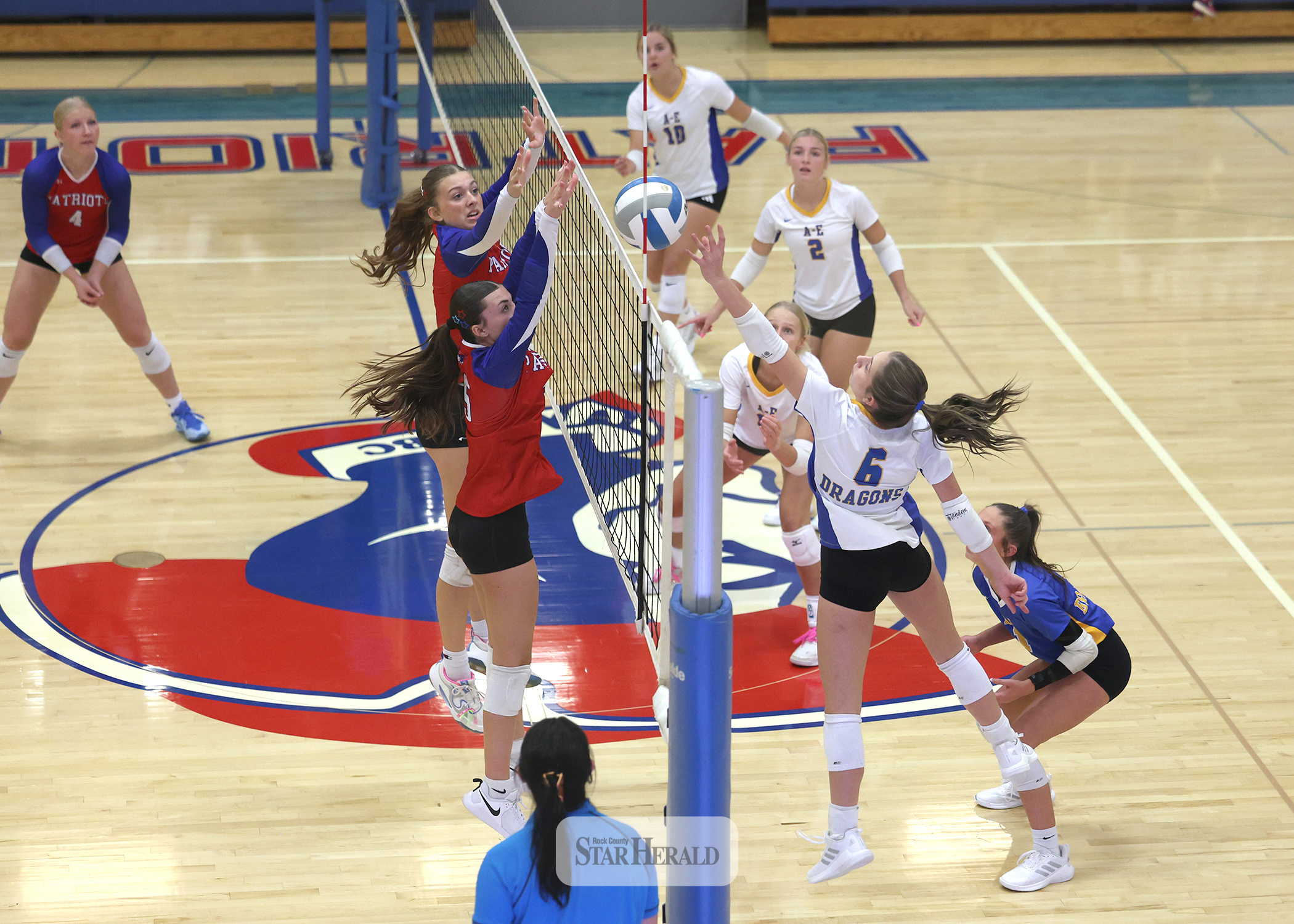 Greg Hoogeveen photo/1008HBCAEVB2 A-E junior Jordan Kruger reaches for a ball at the net as H-BC players junior Aspyn Bartels and senior Ava Steinhoff jump to block any shot over the net. The Adrian-Ellsworth Dragons beat the Hills-Beaver Creek Patriots 3-0 in the match at Hills.