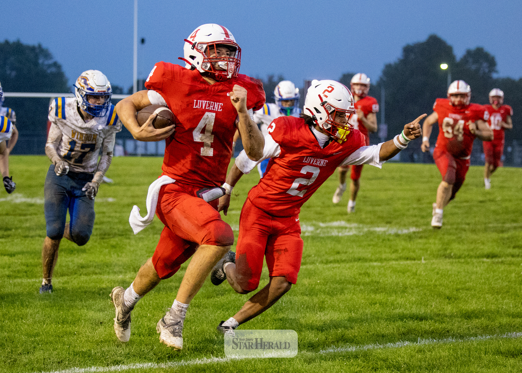 Greg Hoogeveen photo/0924LHSFB1 LHS senior Ben Hartquist runs along the sideline on his way to the end zone flanked by senior Jaymyn McLaughlin Friday, Sept. 18, in Luverne. LHS beat Windom 47-3 in the game.
