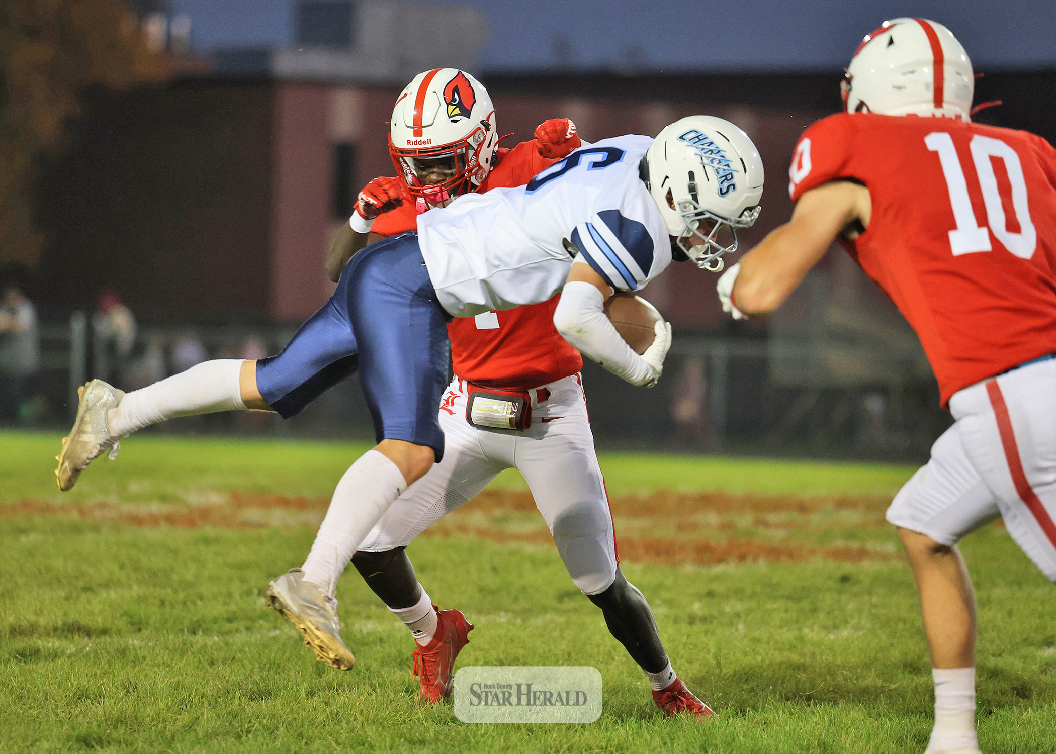 Greg Hoogeveen photo/LHSFB1 LHS senior Darius Dolo knocks a Minnesota Valley Lutheran player into the air with senior Coy Thone, No. 10, covering the tackle. The Cardinals beat the Chargers 56-25 at home Oct. 9.