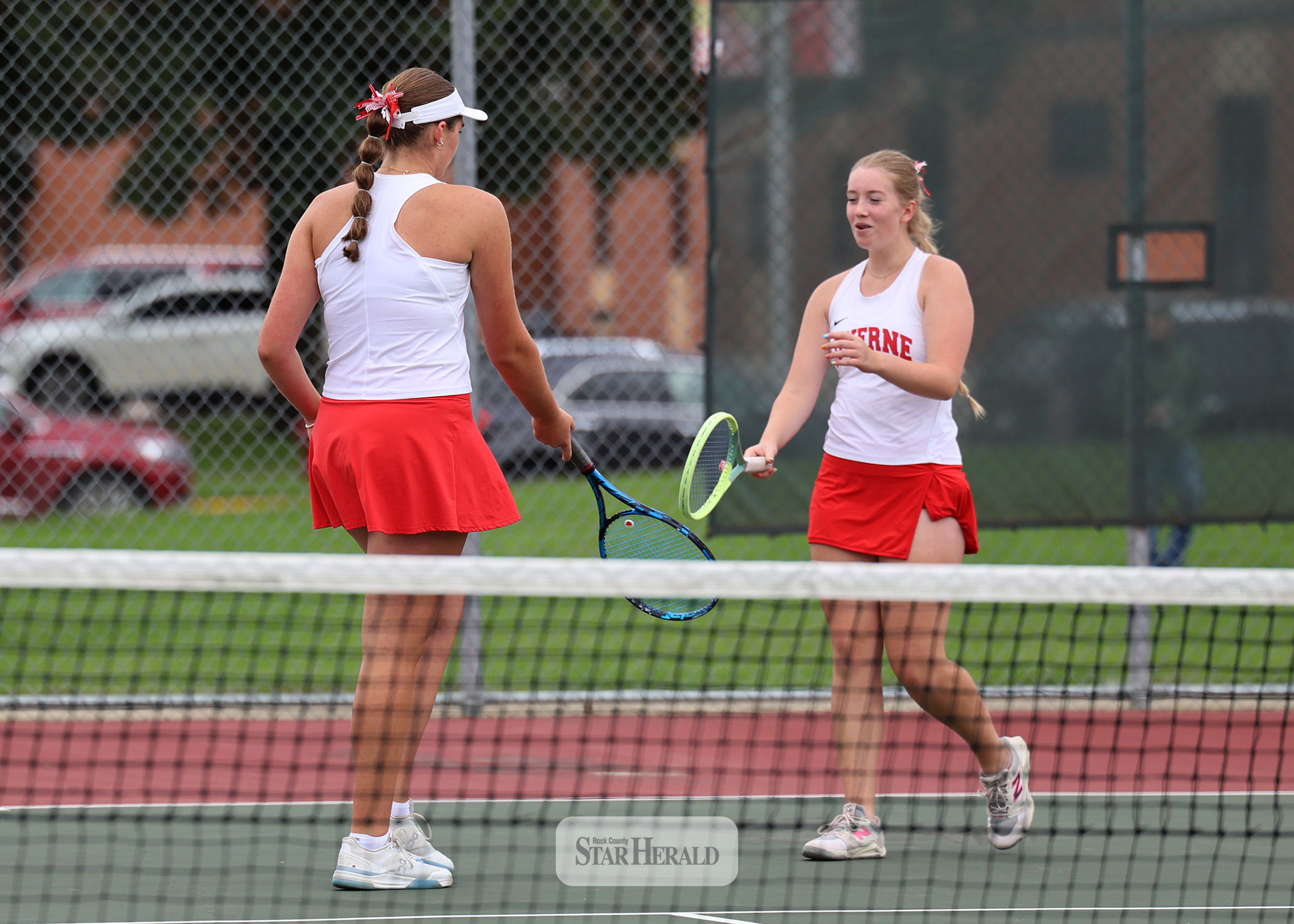 Greg Hoogeveen photo/LHStennis1 Sophomores Gracyn Woodley, left, and Lilly Lanoue tap rackets after scoring a point against Lincoln Tuesday, Sept. 22, at home. The duo won two sets in No. 1 doubles play