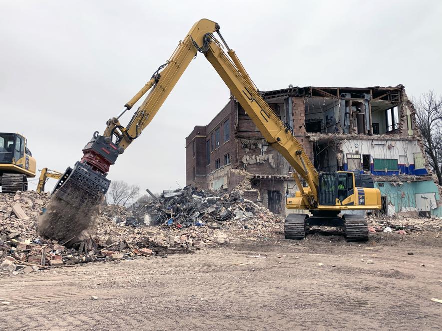Brad McColley with DRC Inc. of Litchfield drops material from the former Hills High School in Hills Monday. The demolition of the 32,808-square-foot building is entering its second week. Mavis Fodness/Rock County Star Herald Photo