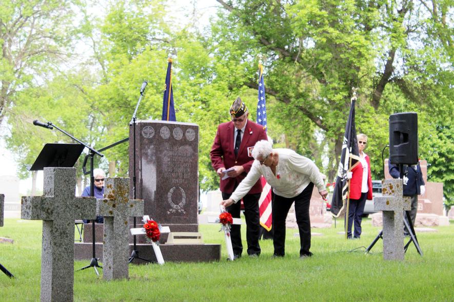 Auxiliary president Dianna Tomlinson (right) places the floral tribute with the assistance of Pat Baustian. Mavis Fodness/Rock County Star Herald Photo