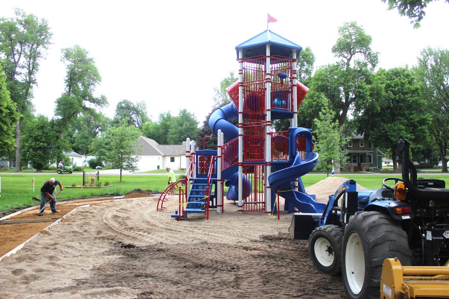 Howard Vis (left) and Rod Verhey work on the landscaping around the new play system Thursday afternoon, June 5, at Jacobson Park in Hills. Mavis Fodness/Rock County Star Herald Photo
