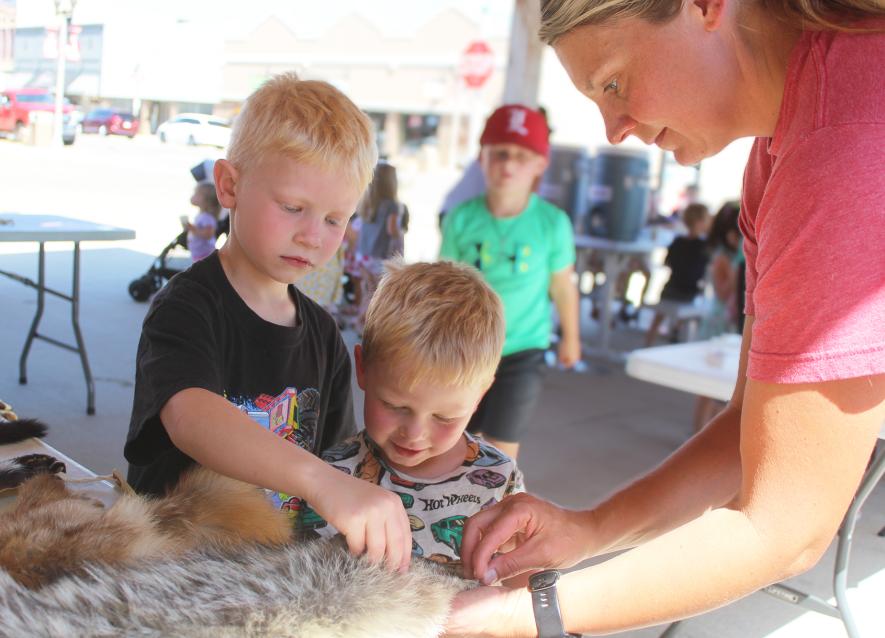 Sylas Frahm (left), cousin Ty Frahm, and his mother, Heather Frahm, take a close look at the coyote hide. Rock County Star Herald Photo