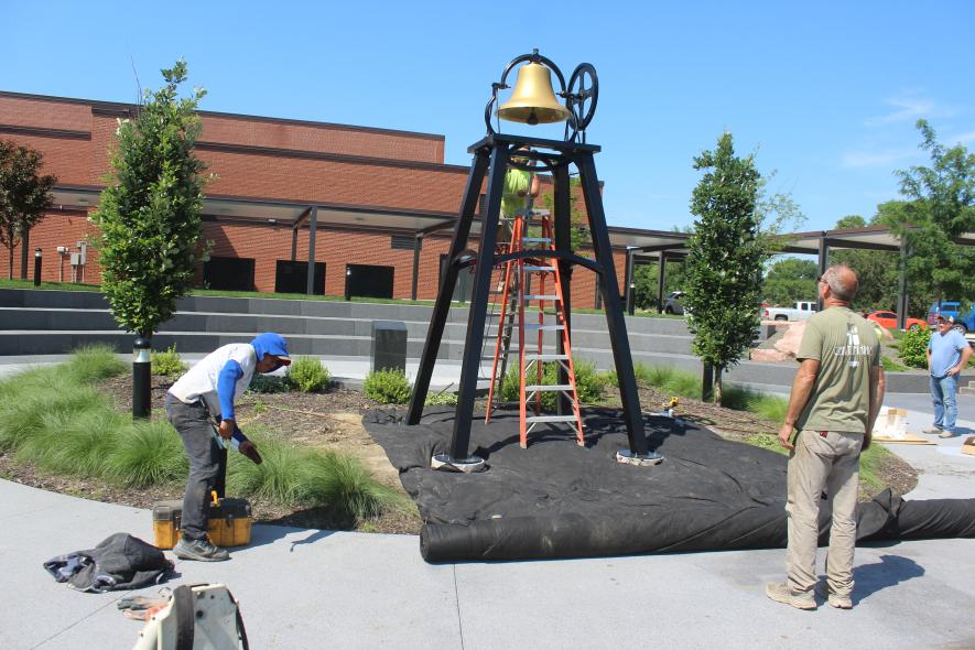 Final adjustments were made Friday afternoon on the school bell now located in the Luverne High School Alumni Garden. Pictured (from left) are Oh’Landscapes workers Gustavo Esteba and Levi Beck, Dassel-Cokato High School teacher Steve Ellis, and Luverne Public Schools building and grounds manager Cory Schmuck. Mavis Fodness/Rock County Star Herald Photo