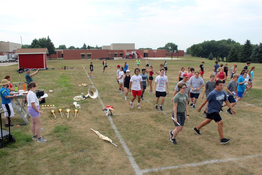 Luverne High School band students drill Monday morning on the school practice field as (far left, from left) colorguard adviser Gavin Folkestad, drum major Elizabeth Mulder, director James Jarvie and drum major Bri Kinsinger watch. The students are in their third week of a three-week band camp. Mavis Fodness/Rock County Star Herald Photo