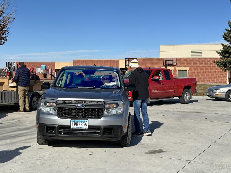 Rock County Veterans Services Officer Eric Oye hands a pork loin through the car window to Willie Nath Monday in the Luverne Elementary School bus parking lot. Nath was among hundreds of local veterans who received pork loins from PMP Monday. Lori Sorenson/Rock County Star Herald Photo