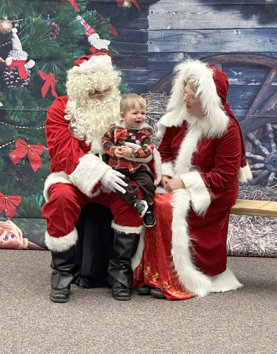 Kayden Brands isn’t happy about his moment with Santa and Mrs. Claus (Bryce Niessink and Janice Fick). Lori Soreson/Rock County Star Herald Photo