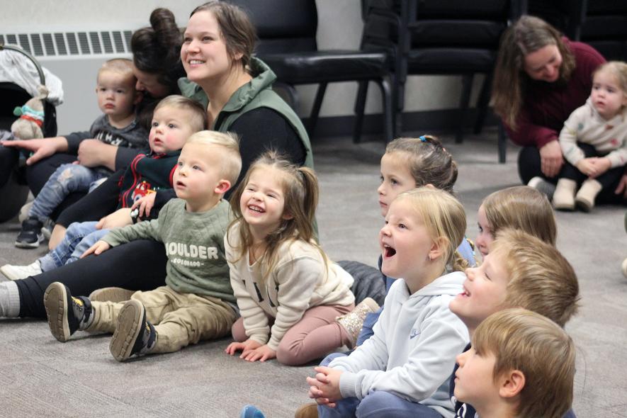 Audience members react to the library puppets on stage. Pictured (from left) are Breanna Schilling holding Finley Schilling, Taborah Nelson holding Gideon Nelson, Isaac Nelson, Daya Schilling, Gabby Grijalva, Brynnley Klarenbeek, Rylann Roozenboom, Eric Richters and Jackson Sparks. Mavis Fodness/Rock County Star Herald Photo