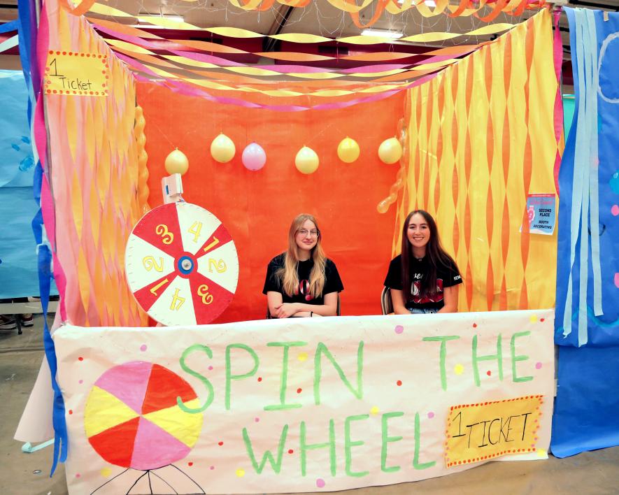Junior Bethany Behr (left) and Rayann Remme earned second place in the booth decorating contest with their "Spin the Wheel" booth in the high school gym during Winter Carnival. Greg Hoogeveen/Rock County Star Herald Photo
