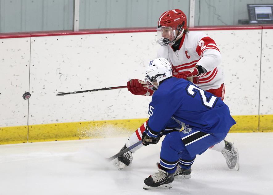 Greg Hoogeveen photo/LHSBHOC1 LHS senior Jaxon Lais and a Minnesota River player rush the puck as it heads toward the boards. Luverne beat the Bulldogs 7-3 Saturday, Jan. 10, in Luverne.