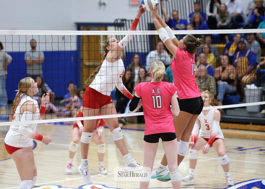 Cardinal senior Greta McClure and an Adrian blocker meet above the net in volleyball action Friday, Oct. 10, in Adrian.