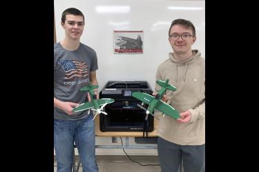 Engineering technology students Coulter Thone (left) and Tucker Banck hold their completed P-47 Thunderbolt model planes. Wood was used to construct the model’s body, main wing and tail wing with accessories designed and made from plastic using the Makerbot 3-D printer pictured in the background. Submitted Photo
