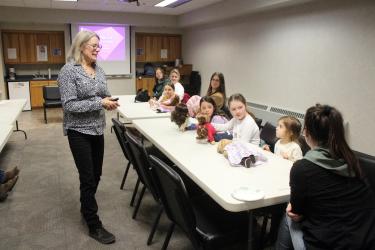 Participants to Monday night’s author visit with Mary Casanova (pictured, standing) introduced themselves and the dolls they brought to the event at the Rock County Community Library. Pictured at the table (from right) are Angela Kemp, Celia Mae Kemp (doll Kit), Madison Peters (Macy), Isabella Nolz (Hermione), Danae Meinerts, Piper Meinerts (Maria), Wendy Peters and Angela Nolz. Mavis Fodness/Rock County Star Herald Photo