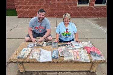 Britton Stratton (left) and Beth Capistran pose with the materials placed in the time capsule when the current Luverne Elementary School opened in November 1998. Stratton was a kindergartner 25 years ago and Capistran has been a music teacher until her retirement this year. Most of the materials sealed in a plastic tub and placed in the stone bench were ruined by moisture. Submitted Photo