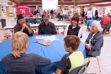 Veterans Jerry Wieman (left) and Dave Banck and their spouses, Diane Banck and Beth Wieman, share stories about military service with fifth-graders Kullen Radisewitz and Sawyer Nath. Mavis Fodness/Rock County Star Herald Photo