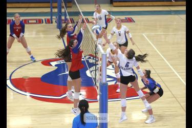 Greg Hoogeveen photo/1008HBCAEVB2 A-E junior Jordan Kruger reaches for a ball at the net as H-BC players junior Aspyn Bartels and senior Ava Steinhoff jump to block any shot over the net. The Adrian-Ellsworth Dragons beat the Hills-Beaver Creek Patriots 3-0 in the match at Hills.