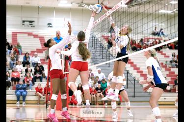 Greg Hoogeveen photo/LHSAE1 LHS sophomore Emma Cowell jumps to lift the ball as A-E sophomore Charlee Hehnhoff follows through with a spike attempt above the net Thursday, Oct. 22, in Luverne. The Dragons beat LHS 3-0 in the Cardinals final match of the regular season.