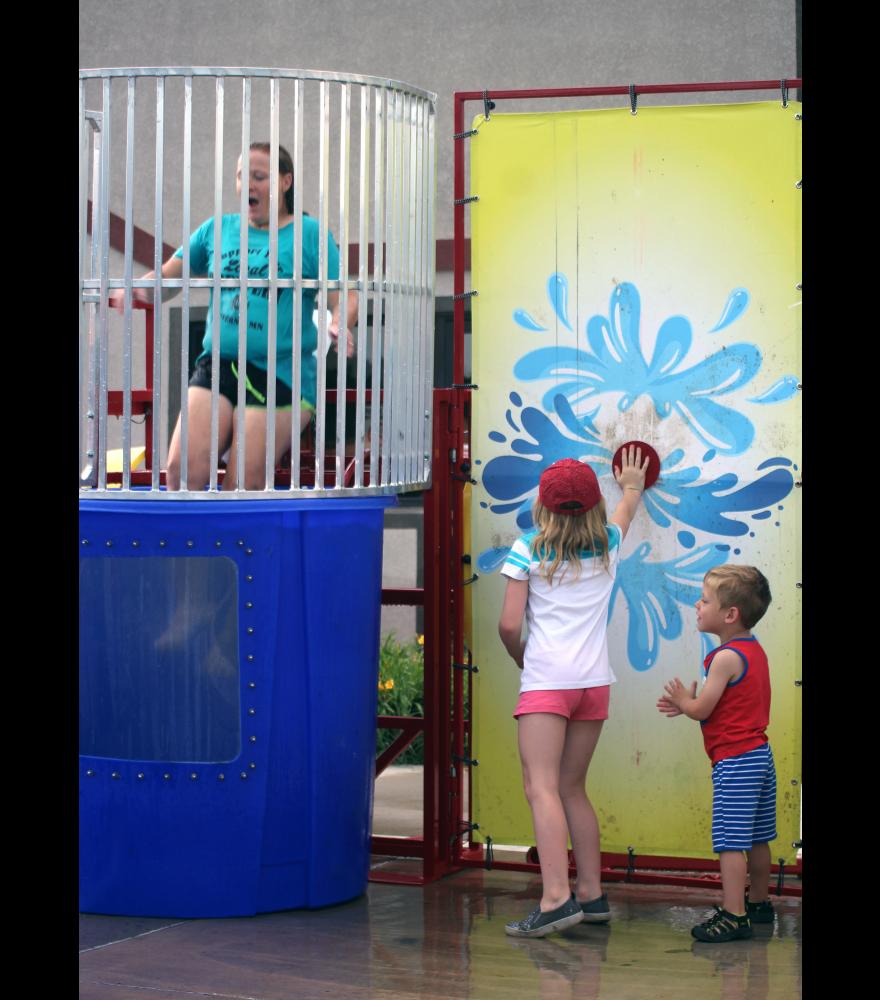 Felicity Woodley, pictured with brother Aidan, presses the button to release a surprised Brenda Johnson, the family’s day care provider, into the dunk tank. Johnson and others at Take 16 Brewery took turns at the fundraiser for the Luverne Area Community Foundation.